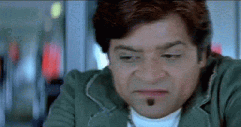 A Man With A Beard Is Making A Funny Face While Wearing A Green Jacket And A White Shirt . GIF