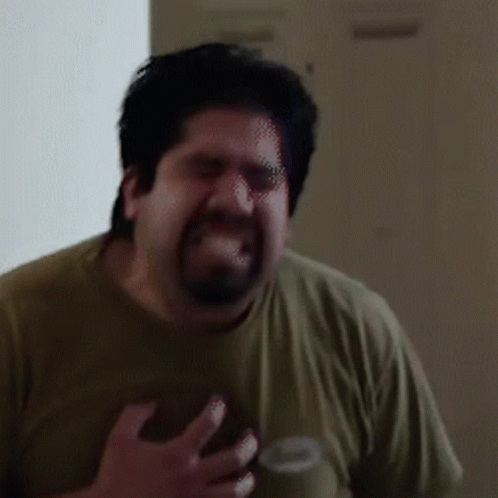A Man With A Beard Is Making A Funny Face While Wearing A Green Shirt GIF