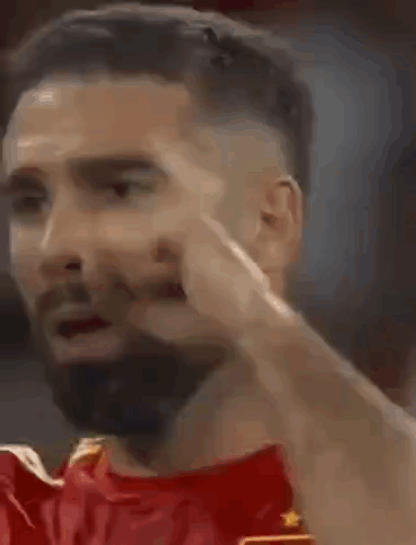 A Man With A Beard Is Making A Funny Face While Wearing A Red Shirt . GIF