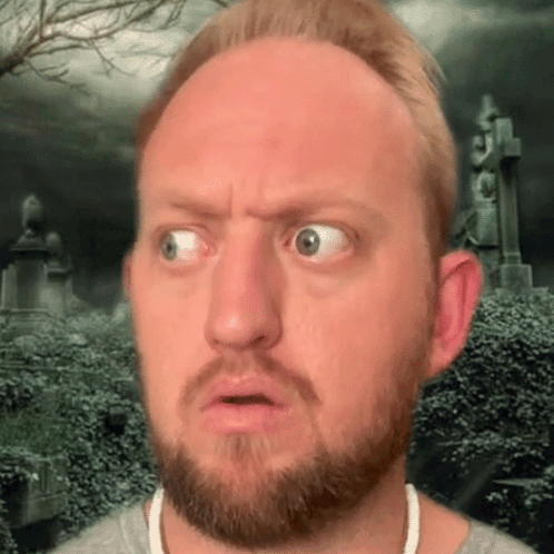 A Man With A Beard Is Making A Funny Face With A Cemetery In The Background GIF