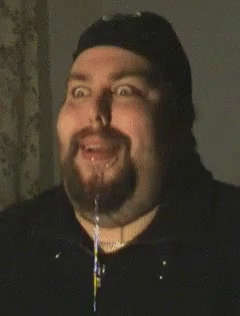 A Man With A Beard Is Making A Funny Face With A Stream Of Liquid Coming Out Of His Mouth GIF