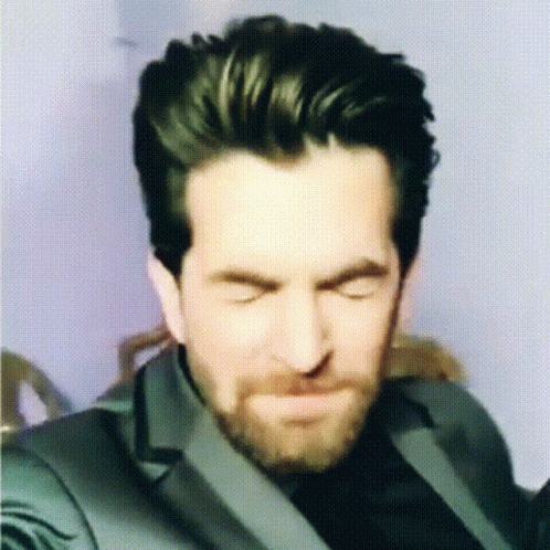 A Man With A Beard Is Making A Funny Face With His Eyes Closed GIF