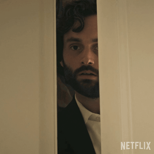 A Man With A Beard Is Peeking Out Of A Door That Says Netflix On The Bottom GIF