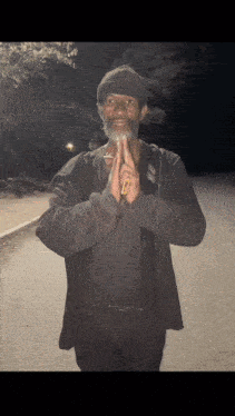A Man With A Beard Is Praying With His Hands Folded In Front Of Him GIF