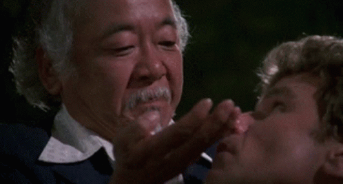 A Man With A Beard Is Putting Something In Another Man 'S Nose GIF