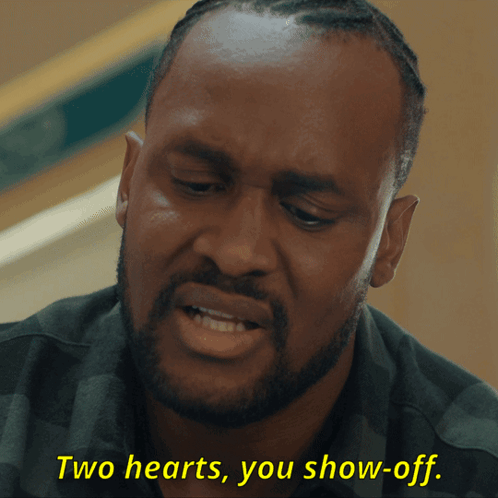 A Man With A Beard Is Saying Two Hearts You Show Off GIF