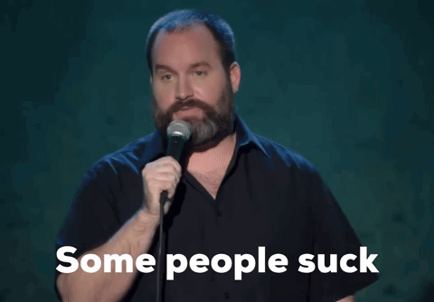 A Man With A Beard Is Singing Into A Microphone With The Words " Some People Suck " Below Him GIF