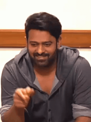 A Man With A Beard Is Sitting At A Table And Eating A Sandwich . GIF