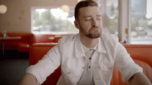 A Man With A Beard Is Sitting At A Table In A Diner . GIF