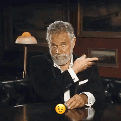 A Man With A Beard Is Sitting At A Table With A Smiley Face In Front Of Him GIF