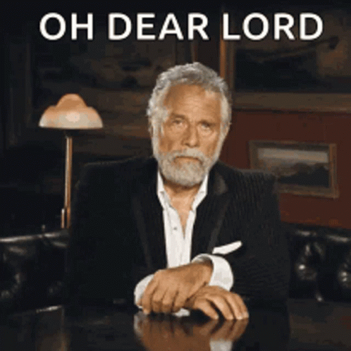 A Man With A Beard Is Sitting At A Table With The Words Oh Dear Lord Behind Him GIF