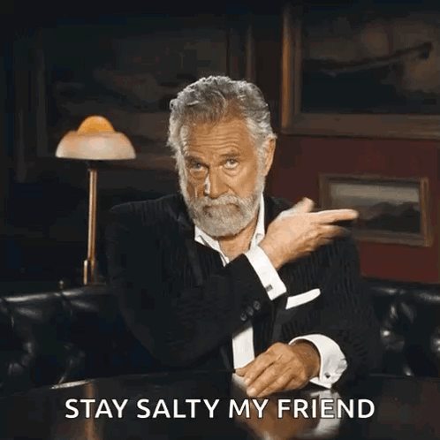 A Man With A Beard Is Sitting At A Table With The Words " Stay Salty My Friend " Written Below Him GIF