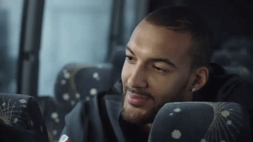 A Man With A Beard Is Sitting In A Bus Seat GIF