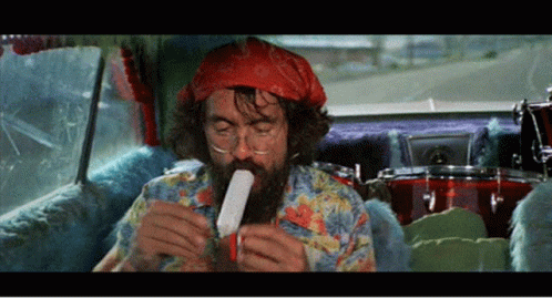 A Man With A Beard Is Sitting In A Car Eating A Popsicle GIF