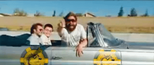 a man with a beard is sitting in a car with two other men .
