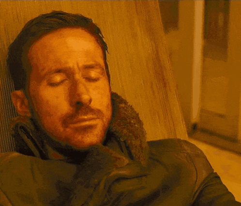 A Man With A Beard Is Sitting In A Chair And Looking At The Camera GIF