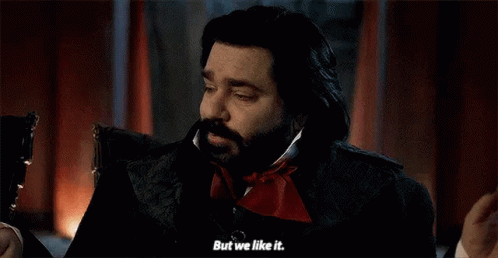 a man with a beard is sitting in a chair and talking to another man .