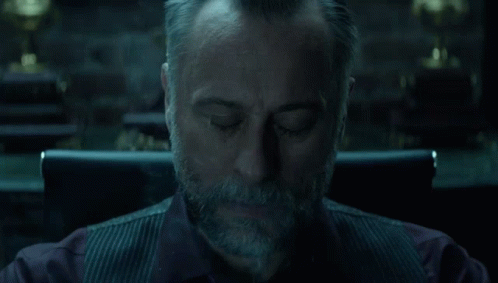 A Man With A Beard Is Sitting In A Chair With Smoke Coming Out Of His Mouth . GIF