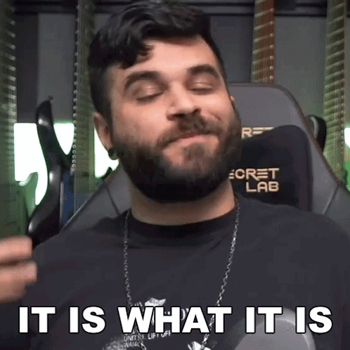 A Man With A Beard Is Sitting In A Chair With The Words " It Is What It Is " Above Him GIF