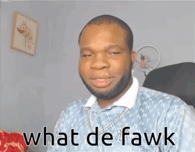 A Man With A Beard Is Sitting In A Chair With The Words What De Fawk Written On His Face GIF