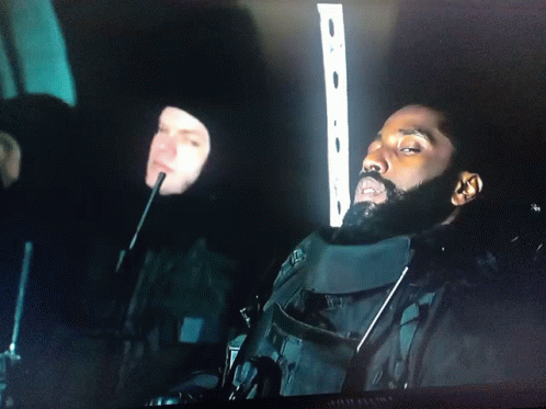A Man With A Beard Is Sitting In A Dark Room Next To Another Man With A Microphone GIF