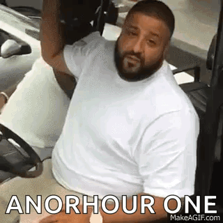 A Man With A Beard Is Sitting In A Golf Cart With The Words `` An Hour One '' Written On It . GIF