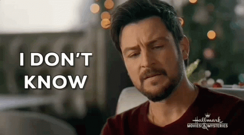 A Man With A Beard Is Sitting In Front Of A Christmas Tree And Saying `` I Don 'T Know '' . GIF