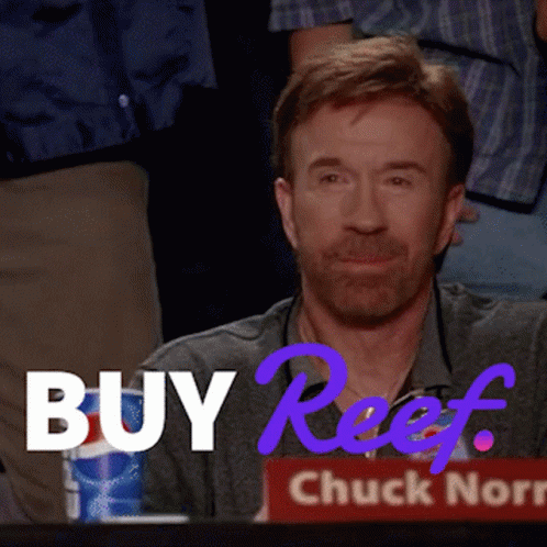 A Man With A Beard Is Sitting In Front Of A Sign That Says Buy Reef GIF