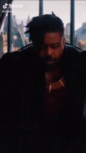 A Man With A Beard Is Sitting In Front Of A Window . GIF