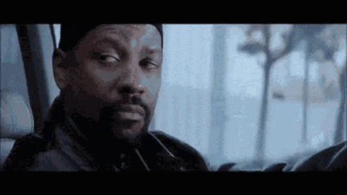 A Man With A Beard Is Sitting In The Back Seat Of A Car Looking Out The Window . GIF