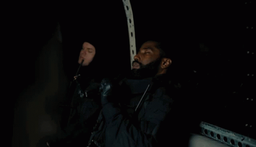 A Man With A Beard Is Sitting In The Dark Holding A Gun GIF