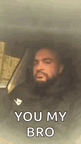 A Man With A Beard Is Sitting In The Driver 'S Seat Of A Car . GIF