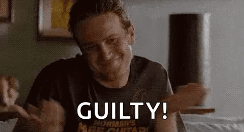 A Man With A Beard Is Sitting On A Bed With His Hands Outstretched And The Words `` Guilty ! '' GIF