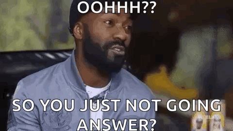 A Man With A Beard Is Sitting On A Couch And Making A Funny Face While Talking To Someone . GIF