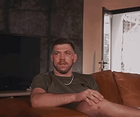 A Man With A Beard Is Sitting On A Couch In Front Of A Television GIF