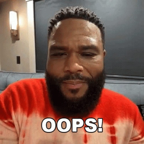 A Man With A Beard Is Sitting On A Couch Wearing A Red Tie Dye Shirt And Saying Oops . GIF
