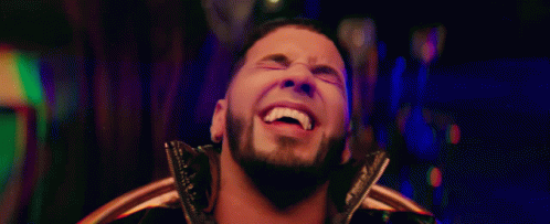 A Man With A Beard Is Smiling And Looking At The Camera GIF