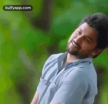 A Man With A Beard Is Smiling And Looking At The Camera . GIF