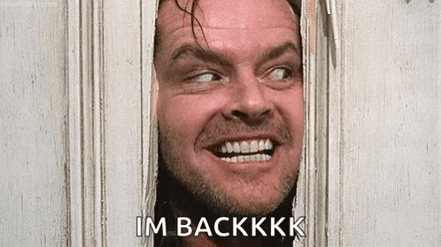 A Man With A Beard Is Smiling And Looking Through A Hole In A Door . GIF
