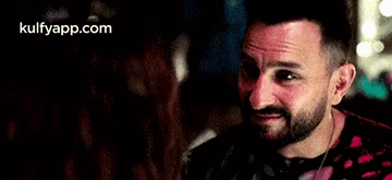 A Man With A Beard Is Smiling At A Woman In A Restaurant . GIF