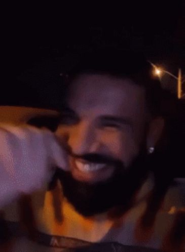 A Man With A Beard Is Smiling In A Car At Night GIF