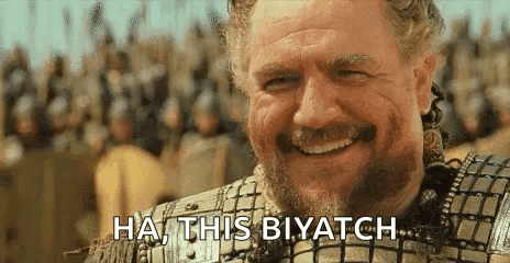 A Man With A Beard Is Smiling In Front Of A Crowd And Saying `` Ha , This Biyatch '' . GIF