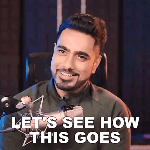A Man With A Beard Is Smiling In Front Of A Microphone And Says Let 'S See How This Goes GIF