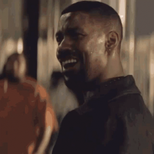 A Man With A Beard Is Smiling In Front Of A Sign That Reads Alright GIF