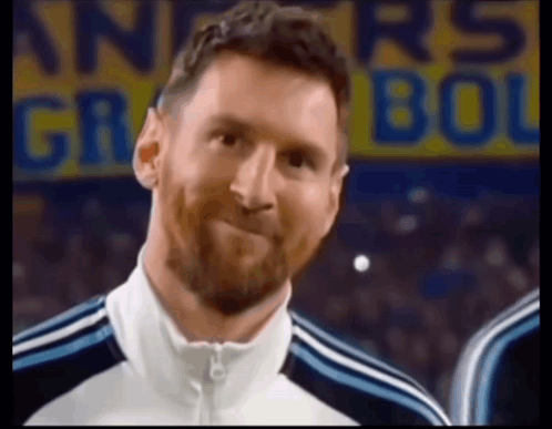A Man With A Beard Is Smiling In Front Of A Sign That Says ' Argentina ' On It GIF