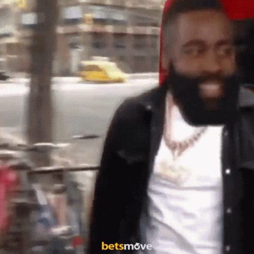 A Man With A Beard Is Smiling In Front Of A Sign That Says Betsmove On It GIF