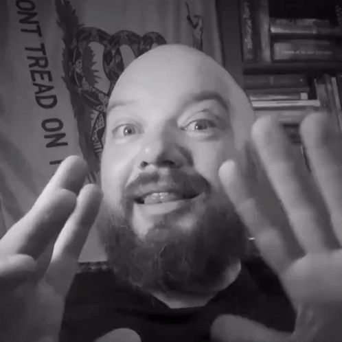 A Man With A Beard Is Smiling In Front Of A Sign That Says " Dont Tread On " GIF