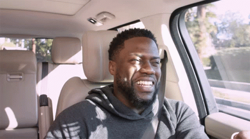 A Man With A Beard Is Smiling While Sitting In A Car GIF