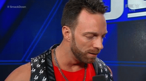A Man With A Beard Is Smiling While Talking Into A Microphone . GIF