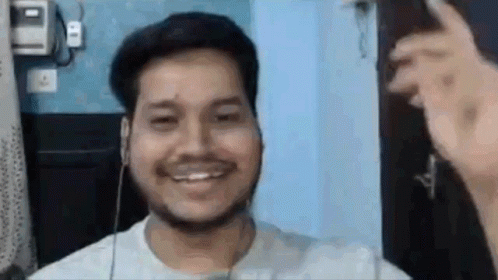 A Man With A Beard Is Smiling While Wearing Headphones And A White Shirt . GIF